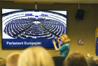 Kobieta w trakcie wykładu. W tle napis Parlament Europejski. 