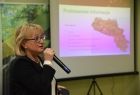 Wójt gminy Sękowa Małgorzata Małuch, podczas prezentacji slajdów, W tle widać slajd na którym pokazana jest jedna z zakończonych inwestycji w gminie Sękowa. 