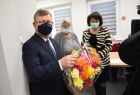 Marszałek Witold Kozłowski podczas spotkania z seniorami w Męcinie wielkiej, na drugim planie widać radną wojewódzką Jadwigę Wójtowicz. Marszałek trzyma w ręku koszyk z ręcznie wykonanymi papierowymi kwiatami. 