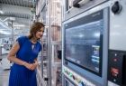 Marta Malec-Lech z zarządu województwa stoi w hali produkcyjnej obok dużego monitora.
