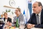 Widok na 2 kobiety i mężczyznę siedzących przy stole. 