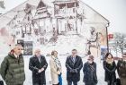 Goście wydarzenia stoją przed budynkiem podczas odsłonięcia muralu