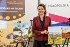 Marta Malec-Lech z zarządu województwa stoi i trzyma obraz. W tle widoczny napis Małopolska.