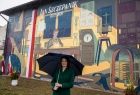 Marta Malec-Lech z zarządu województwa stoi z parasolem, bo pada deszcz. Z tyłu widoczny mural.
