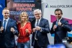 Uczestnicy na tle banerów Małopolski