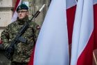 Żołnierz stoi obok flagi Polski.