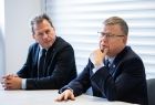Wójt Moszczenicy spogląda na Marszałka Witolda Kozłowskiego. Mężczyźni siedzą przy białym stole. 
