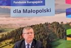 Marszałek Województwa Małopolskiego Witold Kozłowski w trakcie konferencji. W tle za marszałkiem znajduję się ścianka z napisem dla Małopolski ora kolorowe logo województwa. Napis umieszczono na zdjęciu pokazujący górskie regiony województwa. 