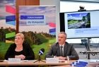 Dyrektor Dep. Funduszy Europejskich UMWM Paweł Knapczyk i dyrektor Dep. Monitorowania Wdrażania Funduszy Europejskich UMWM Joanna Schilbachw trakcie konferencji prasowej. Za nimi znajduję się rzutnik na którym wyświetlono informacje dotyczące inwestycji. 