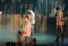 Trzech artystów w trakcie występów. Scena jest delikatnie podświetlona, do minują na niej kolory szarości. 