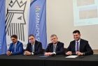 Sygnatariusze siedzą przy stole. W tle widoczna flaga z napisem Małopolska.