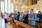 Widok na ołtarz wewnątrz kościoła. W pierwszej ławce stoją Marszałek Witold Kozłowski, poseł Barbara Bartuś i radna Jadwiga Wójtowicz. W tle widoczne są wysokie witrażowe okna świątyni. 