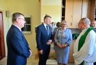 Marszałek Witold Kozłowski, poseł Barbara Bartus i Ksiądz Proboszcz stoją wewnątrz pomieszczenia. 