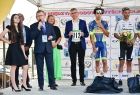 Burmistrz Starego Sącza Jacek Lelek stoi pośród zwycięzców wyścigu kolarskiego, burmistrz trzyma w ręku tabliczkę z numerem. Na pierwszym planie widać Marszałka Witold Kozłowskiego, który trzyma w ręku mikrofon. 