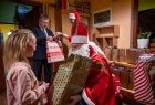 Święty Mikołaj oraz Marszalek Witold Kozłowski wręcza dziewczynce prezent. 