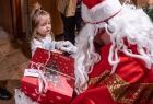 Malutka kilkuletnia dziewczynka odbiera od Świętego Mikołaja prezent. 