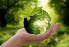 Dłoń trzymająca szklaną zieloną planetę Ziemię, na tle zieleni