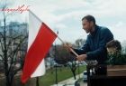 Mężczyzna wywieszający Flagę RP na balkonie, w towarzystwie synka