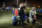 Uchodźcy z torbami i walizkami idą drogą wzdłuż peronu