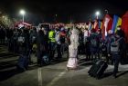Tłum uchodźców stoi z bagażami przed namiotami