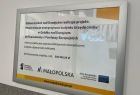 Gmina Gródek nad Dunajcem, zdjęcie tablicy informującej o uzyskaniu dofinansowania z Funduszy Europejskich na modernizację budynku gminy w kwocie 302 042,24 złotych. 