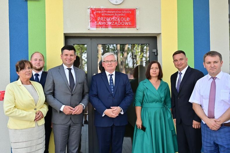 Goście uroczystości pozują do wspólnego zdjęcia na tle budynku przedszkola, wśród nich radna województwa Anna Mikosz, wicemarszałkowie Łukasz Smółka i Józef Gawron