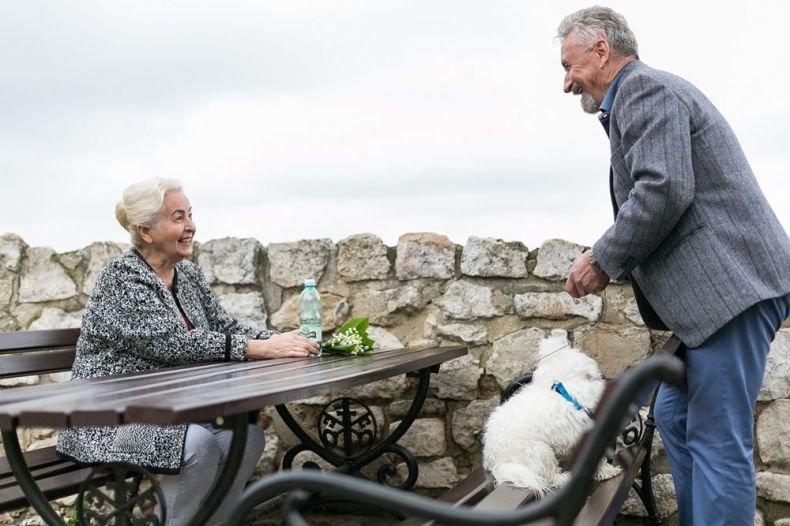 Para seniorów przy stoliku w kawiarni, z psem