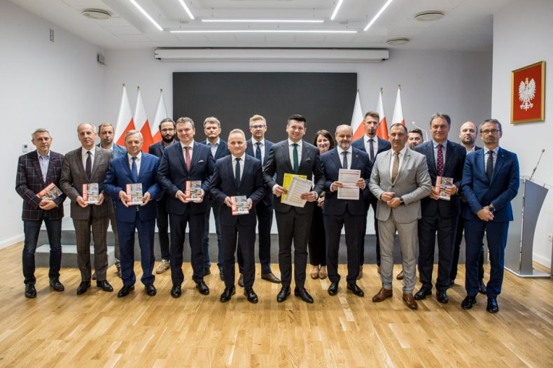 Uczestnicy spotkania stoją razem w sali konferencyjnej.