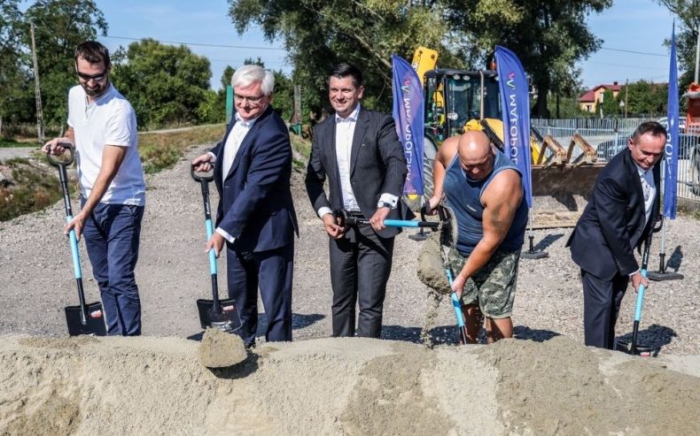 Wicemarszałkowie Łukasz Smółka i Józef Gawron wbijają łopatę z innymi ludźmi. Z tyłu widoczna zieleń.