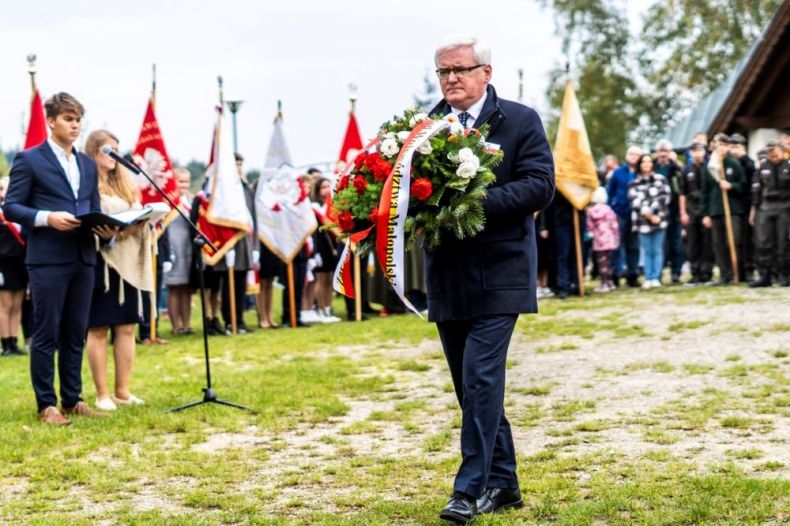 Wicemarszałek Józef Gawron niesie kwiaty. Z tyłu widoczne poczty sztandarowe.