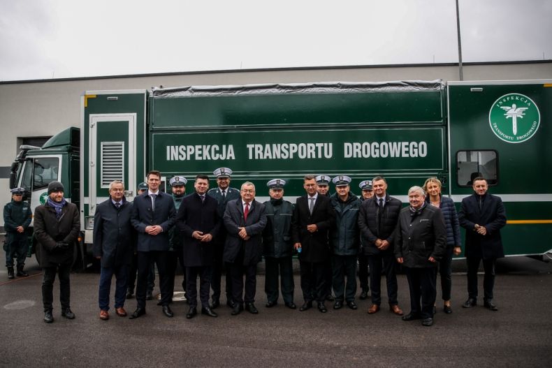 Wicemarszałek Łukasz Smółka stoi z pozostałymi uczestnikami wydarzenia przed pojazdem inspekcji.