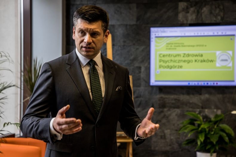 Wicemarszałek Łukasz Smółka przemawia, za nim widoczny ekran z napisem Centrum Zdrowia Psychicznego Kraków-Podgórze.