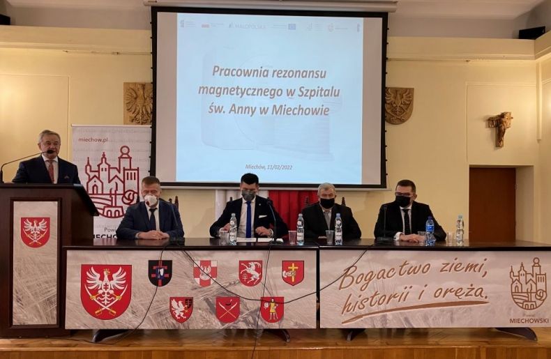 Wicemarszałek Łukasz Smółka i wojewoda Łukasz Kmita siedzą przy stole sali konferencyjnej. Z tyłu widoczny ekran.