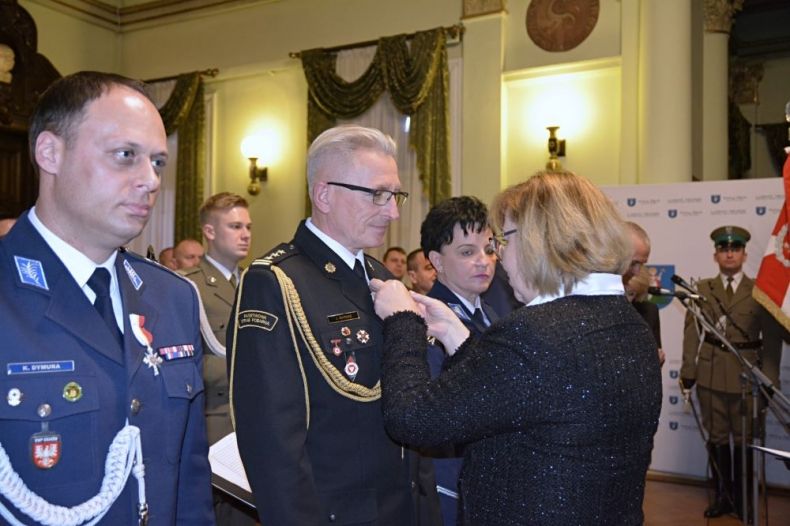 Radna województwa Marta Mordarska przypina odznaczenie do munduru strażakowi.