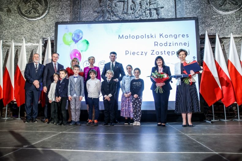 Uczestnicy gali w Wieliczce. Po bokach biało-czerwone flagi.