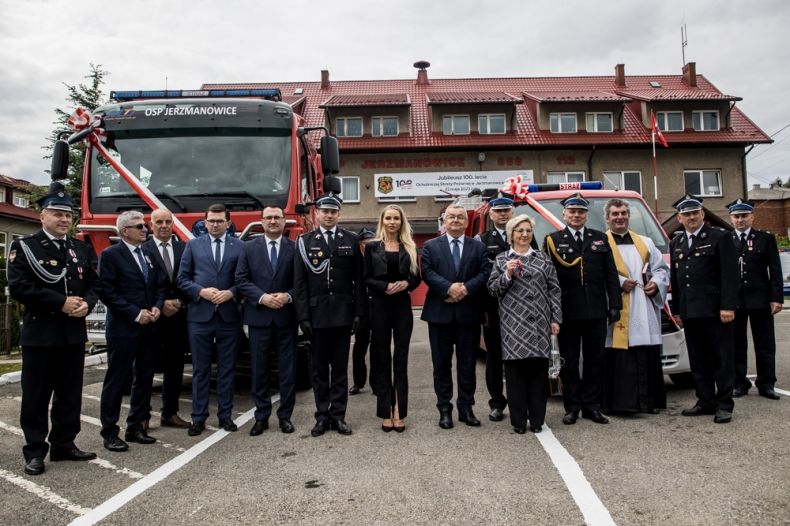 Uczestnicy uroczystości w Jerzmanowicach stoją przed budynkiem OSP. Za nimi widoczny wóz strażacki.