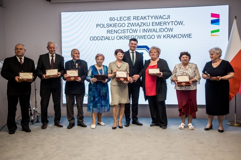 Wicemarszałek Łukasz Smółka stoi na scenie z uczestnikami wydarzenia.