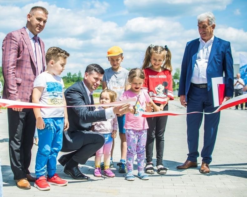 Wicemarszałek Łukasz Smółka wraz z dziećmi przecina wstęgę.