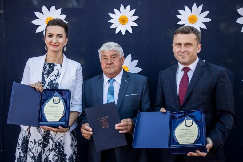 Marta Malec-Lech z zarządu województwa i Wojciech Skruch wiceprzewodniczący sejmiku województwa stoją z mężczyzną i pokazują ozdobne podziękowania.