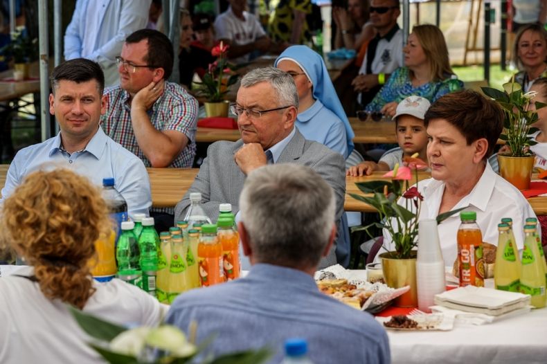 Wicemarszałek Łukasz Smółka siedzi przy stole z europoseł Beatą Szydło i ministrem Andrzejem Adamczykiem.