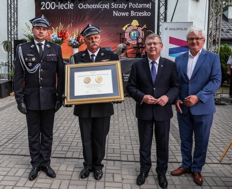 Marszałek Witold Kozłowski i wicemarszałkowie Łukasz Smółka i Józef Gawron stoją ze strażakiem trzymającym medal Polonia Minor.