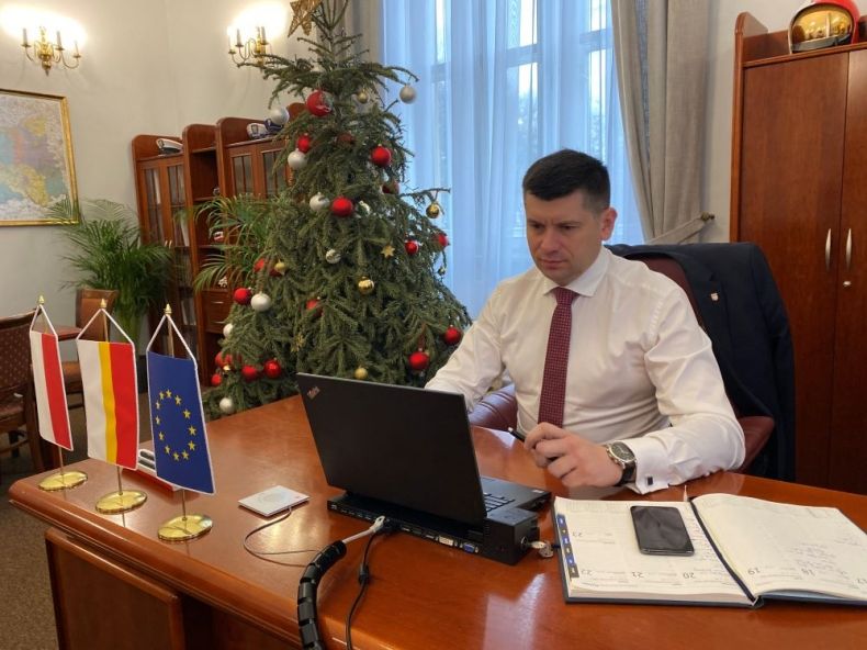 Wicemarszałek Lukasz Smółka siedzi przed komputerem. Z tyłu widoczna świąteczna choinka.