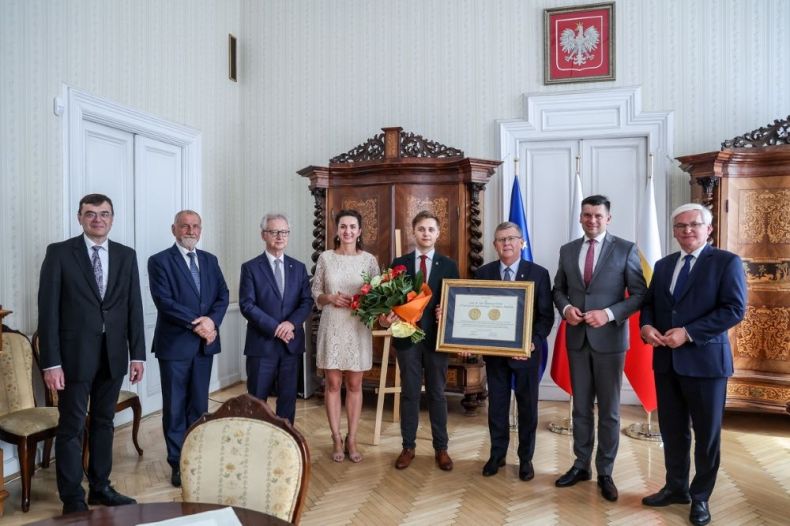 Marszałek Witold Kozłowski trzyma medal Polonia Minor. Obok stoją uczestnicy wydarzenia.