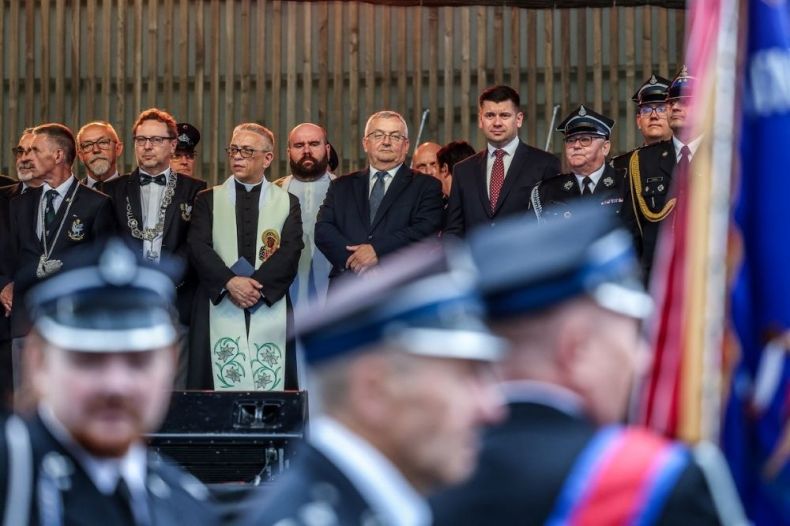 Wicemarszałek Łukasz Smółka i minister Andrzej Adamczyk stoją na scenie. Na pierwszym planie strażacy.