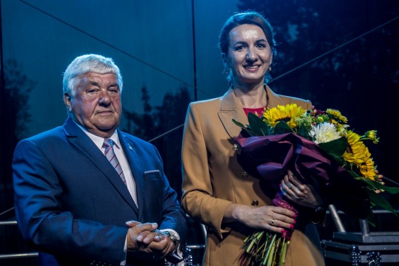 Marta Malec-Lech z zarządu województwa stoi z mężczyzną i trzyma w rękach kwiaty.