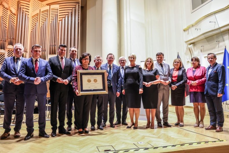 Widok na scenę w filharmonii, Marszałek Witold Kozłowski i przedstawiciele władz samorządowych z Małopolski i Turyngii. Wszyscy pozują do zdjęcia. Marszałek trzyma Medal Polania Minor.