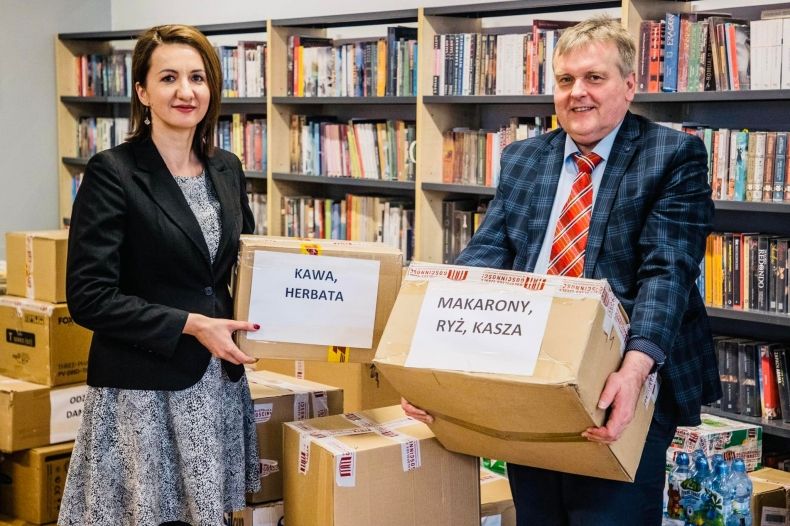 Marta Malec-Lech z zarządu województwa stoi z mężczyzną i trzyma pudełka z darami.