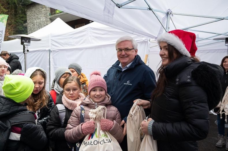 Wicemarszałek Józef Gawron z grupą dzieci trzymających torby z prezentami