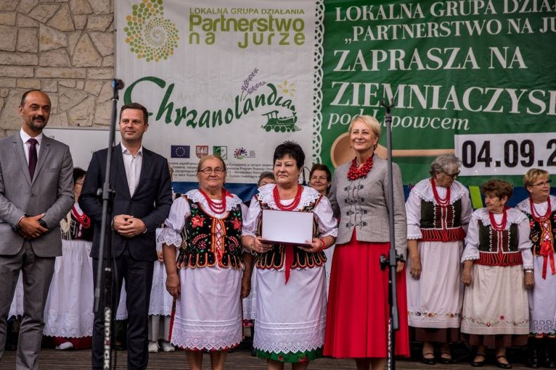 Iwona Gibas na scenie wśród uczestników wydarzenia w regionalnych strojach