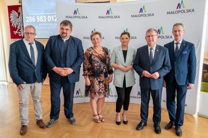 Marszałek Witold Kozłowski, starosta Limanowski Mieczysław Uryga, poseł na sejm RP Patryk Wicher, Bogdan Pałka szef automoto klubu. Wszyscy stoją na tle białej ścianki z logiem w kształcie litery M i napisu małopolska